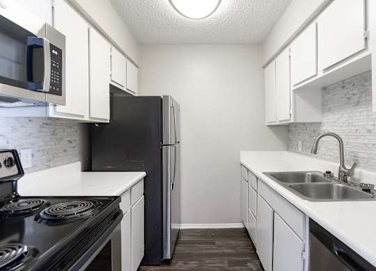 A kitchen with black appliances and white cabinets.