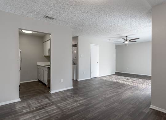 A room with a ceiling fan and a kitchenette.