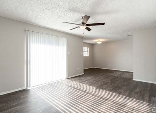A room with a ceiling fan and sliding glass doors.