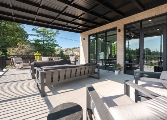 a patio with benches and chairs and glass doors