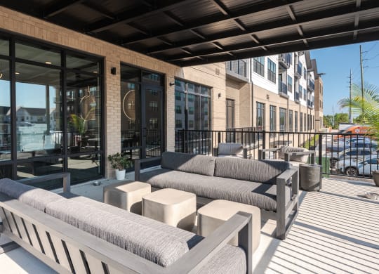 a patio with couches and tables and a building with glass doors