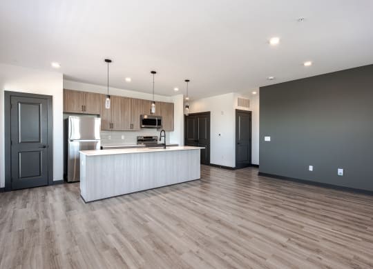 an open kitchen and living room with wood flooring and a white island with a