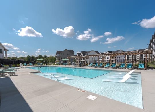 a swimming pool with lounge chairs and a building in the background