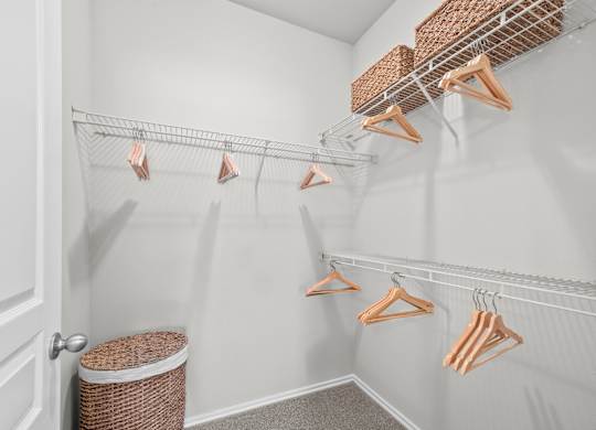 A white closet with clothes hanging on hangers.