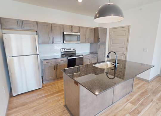 A kitchen with a refrigerator, oven, and microwave.