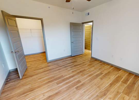 A room with wooden floors and two open doors.