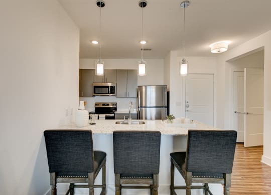 a kitchen with a large island with three chairs in front of it