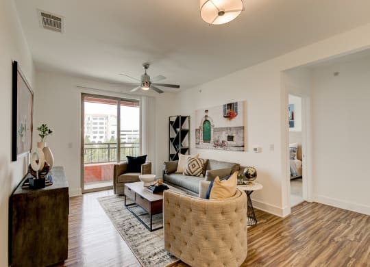 a living room with hardwood floors and a sliding glass door leading to a balcony