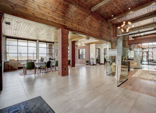 Spacious modern lobby here at 35 Degrees North Apartment Homes with brick pillars, large windows, and warm wood ceiling. Green chairs around desks create a welcoming, airy atmosphere.
