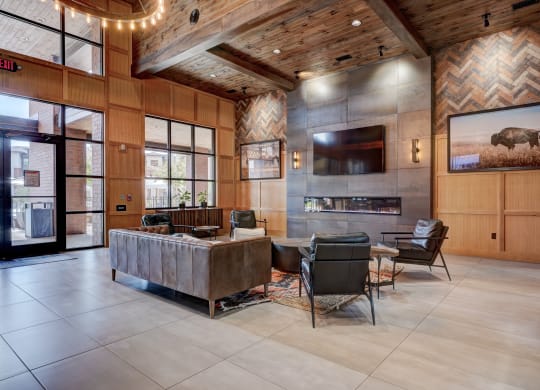 Spacious lobby here at 35 Degrees North Apartment Homes with cozy seating, leather couches, and armchairs. Modern decor includes a wall-mounted TV, fireplace, and buffalo artwork. Warm, inviting ambiance.