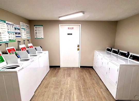 A laundromat with washers and dryers lined up on both sides of the room.