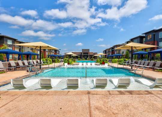 A large outdoor swimming pool surrounded by lounge chairs and umbrellas.