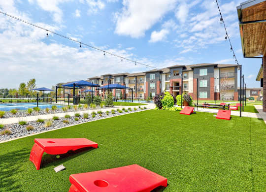 A grassy area with red benches and a pool in the background.