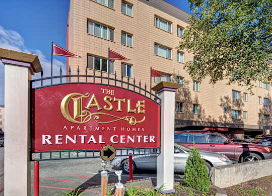 The sign for The Castle Apartment Homes Rental Center is red and gold.