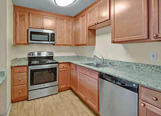 A well-appointed kitchen here at Club at Eagle Pointe featuring warm wood cabinetry, durable countertops, and stainless steel appliances including a range, microwave, and dishwasher. Ample cabinet storage and generous counter space create a functional layout ideal for everyday cooking and entertaining.