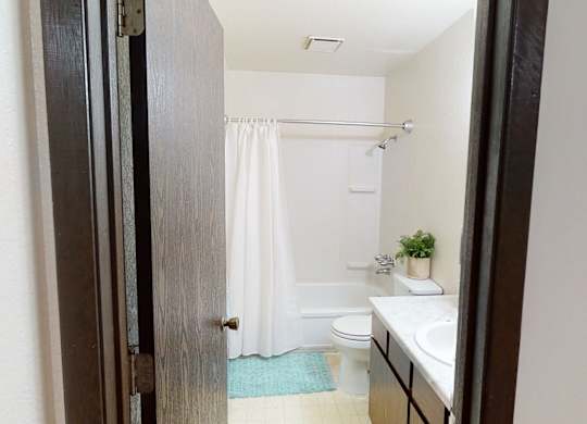 Bright bathroom here at Deer Park featuring a tub and shower combination with white surround, a single-sink vanity with ample counter space, and a toilet neatly arranged for functionality. Neutral wall tones, simple finishes, and overhead lighting create a clean, practical space designed for everyday comfort and convenience.
