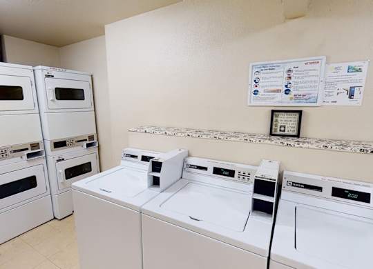 A row of white washers and four stacked dryers on the left. An open space for laundry here at Hillside Chalet.