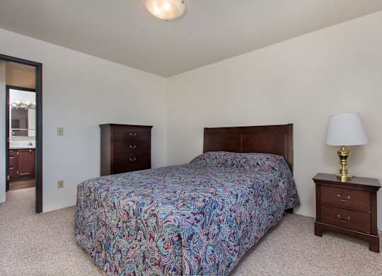 A bedroom with a bed, nightstand, and lamp.