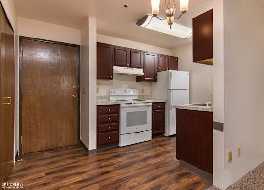 A kitchen with brown cabinets and a white fridge.