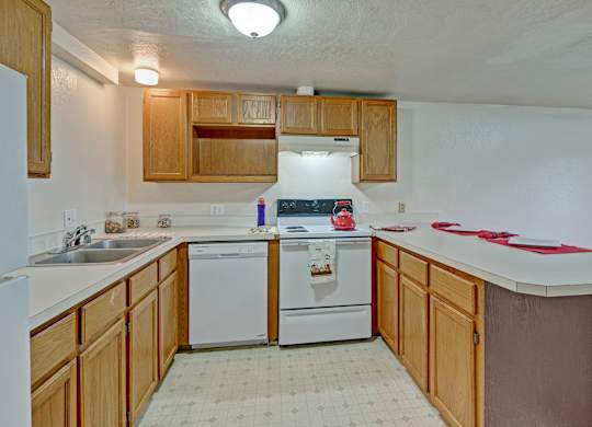 A kitchen with white appliances and wooden cabinets.
