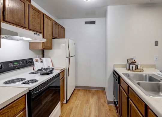 A kitchen with a stove, refrigerator, and sink.