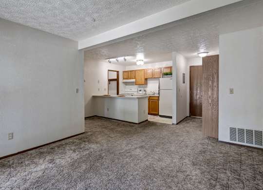 A kitchen area with white walls and a carpeted floor.