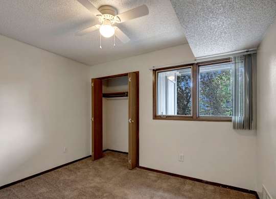 A room with a ceiling fan and a door leading to another room.