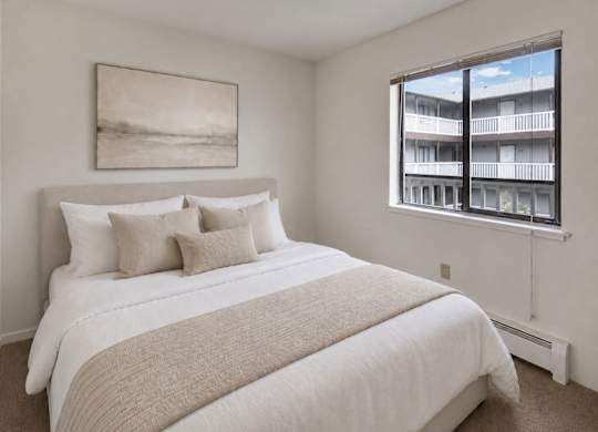 A bedroom with a large bed and a window overlooking a balcony.