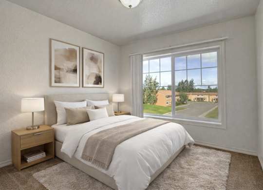 Bright bedroom here at The Glen featuring a neatly made bed with white bedding and neutral throw blanket, matching nightstands with lamps, soft carpet flooring, and a large window that brings in natural light and views of the community grounds.