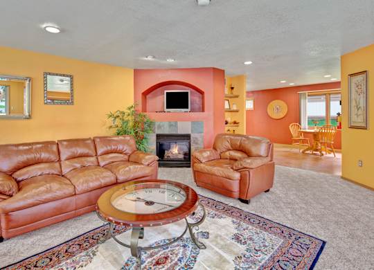 A spacious community lounge here at Wildwood Estates with comfortable leather seating, a cozy fireplace with built-in shelving, and warm accent walls that create an inviting gathering space.