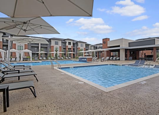 Luxurious pool area at 49 West's modern apartment complex, featuring cushioned lounge chairs and large umbrellas under a clear blue sky, conveying relaxation.