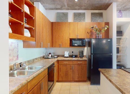 a kitchen with wooden cabinets and a black refrigerator