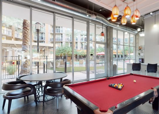 a red pool table in a room with large windows
