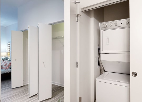 a white washer and dryer in a room with a bedroom in the background