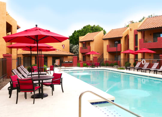 a swimming pool in front of a hotel with chairs and umbrellas