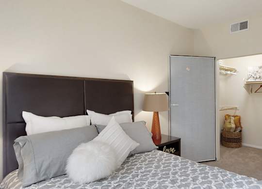 A bedroom with a bed, a nightstand, and a fridge.