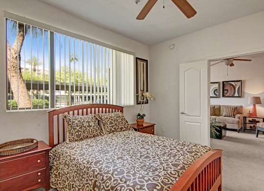 A bedroom with a bed, dresser, and window with blinds.