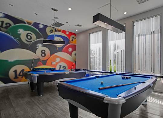 A pool table with a blue cloth and a wall with billiard balls.