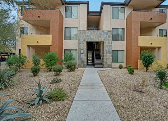 A modern building with a stone entrance and a gravel garden in front.