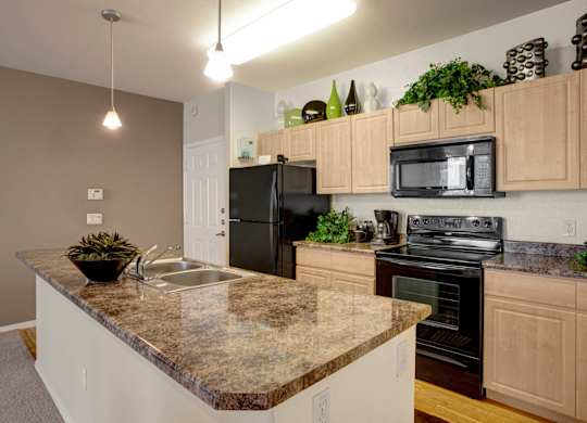 A kitchen with granite countertops and black appliances.