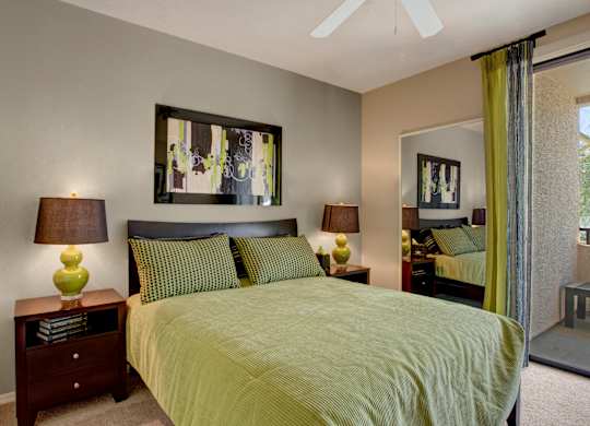 A bedroom with a bed, two lamps, and a painting on the wall.