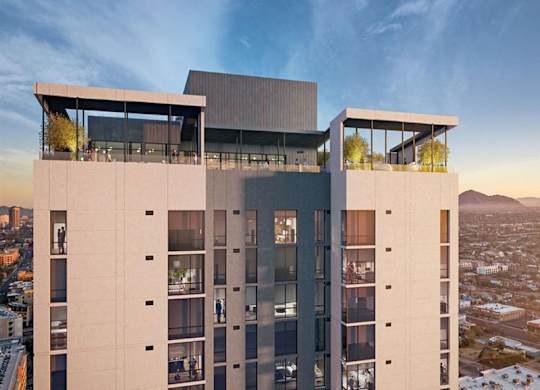 A striking high-rise exterior here at JOY on 4th showcasing modern architecture with clean lines, expansive glass balconies, and a rooftop amenity deck overlooking the city. Floor-to-ceiling windows reflect the sunset sky, while elevated lounge spaces crown the building with panoramic skyline and mountain views.