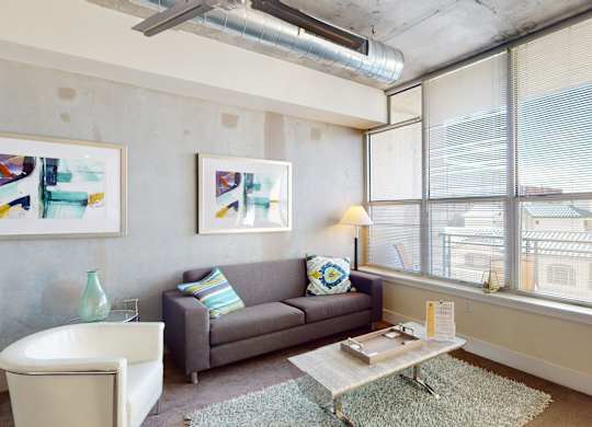 A living room with a grey couch, a white chair, a coffee table, and a painting on the wall.
