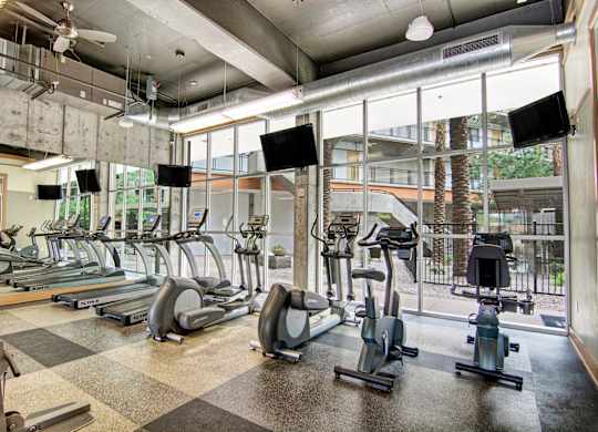 A gym with treadmills, exercise bikes, and a checkered floor.