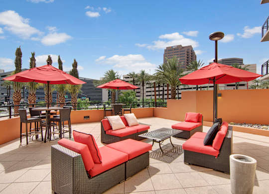 A patio with red cushions and umbrellas.