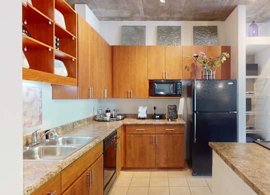 A kitchen with wooden cabinets and a black refrigerator.