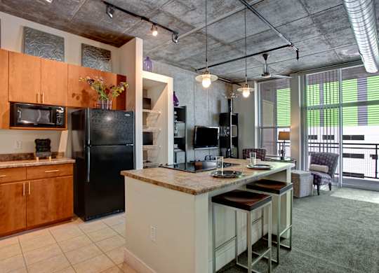 A kitchen with a black refrigerator and a black microwave.