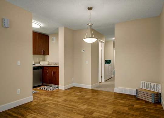 A bright dining area here at 3600 Brentwood with warm wood-style flooring, a modern hanging light fixture, and an open layout that connects to the kitchen and in-unit laundry space.