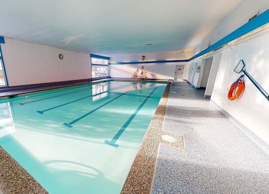 A bright indoor swimming pool here at Cambridge West with clear water, lap lanes, and wide deck space, featuring large windows for natural light and a clean, relaxing atmosphere.
