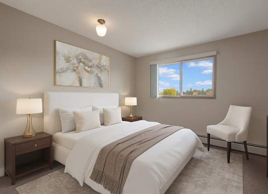 A bright bedroom here at Gateway Square featuring a cozy bed with crisp white bedding and soft neutral pillows, paired with matching nightstands and warm table lamps, plus elegant wall art and a plush accent chair for a calm, relaxing retreat.